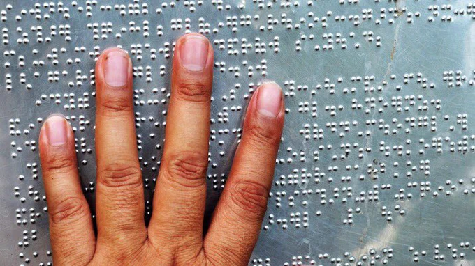 A person's hand on top of a surface of silver brail.