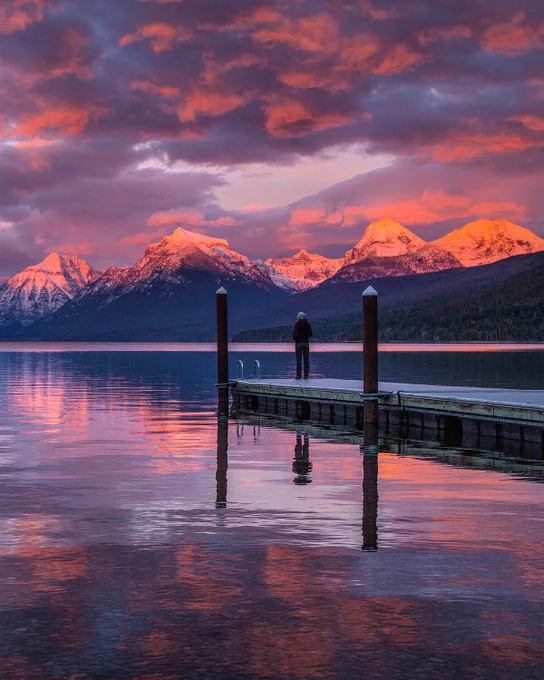 Person stands at the end of dock on a lake