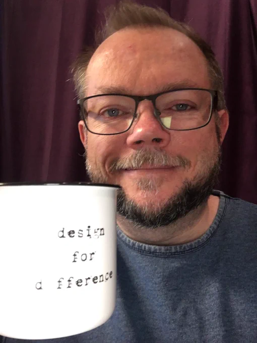 Per Axbom smiling and holding a white mug with the words "design for difference".