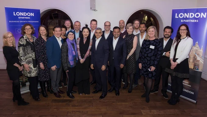 Group shot of people in business dress standing in front of 'London & Partners' pull-up banners. Sadiq Khan is in the centre of the group.