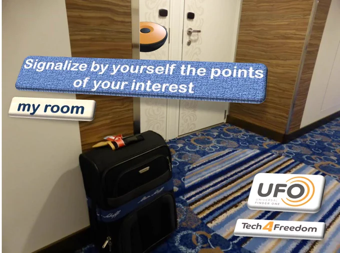 A UFO user  has identified his/her hotel room thanks to the UFO, placed previously by himself, inside the room.  In the picture is seen a hotel corridor with a baggage in front of a room and the UFO behind the door. A floating text says; Signalize by yourself the points of your interest