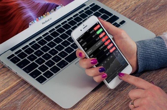 Woman using her phone and MacBook Air to do financial research. Credit: foter.com