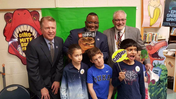 Dr. Repollet meeting students and standing in front of dinosaur posters