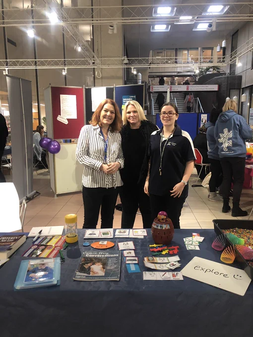 Three ladies at a small exhibition stand with educational games for people with autism.