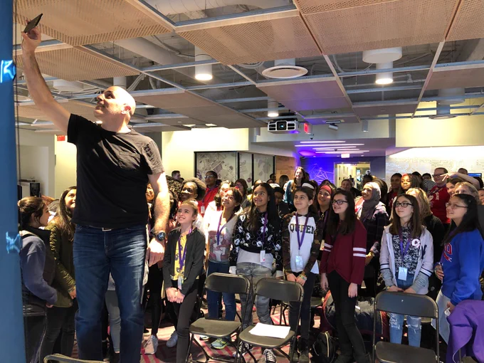 Walmart CEO Marc Lore stands in front a group of girl coders to take a group selfie