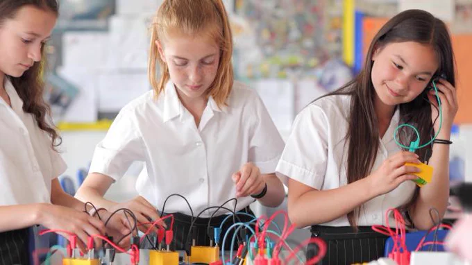 Three girls working with electronics in a classroom