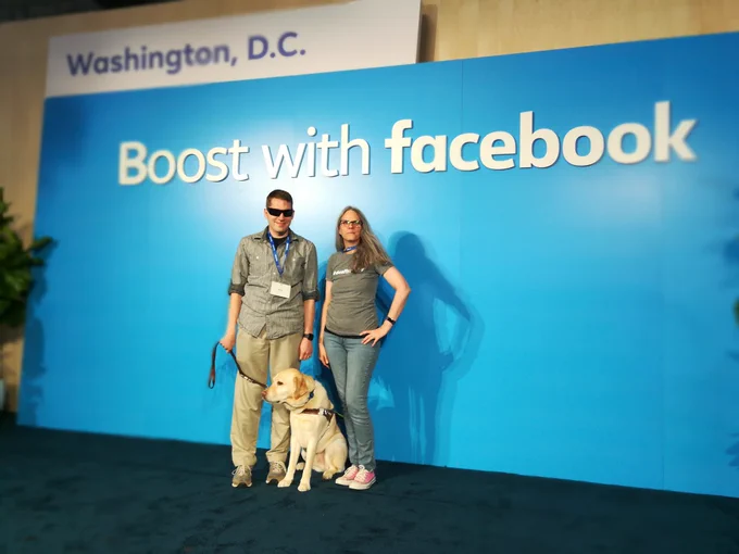 Two people and a service pet in front of blue wall with "Boost with Facebook Washington DC"