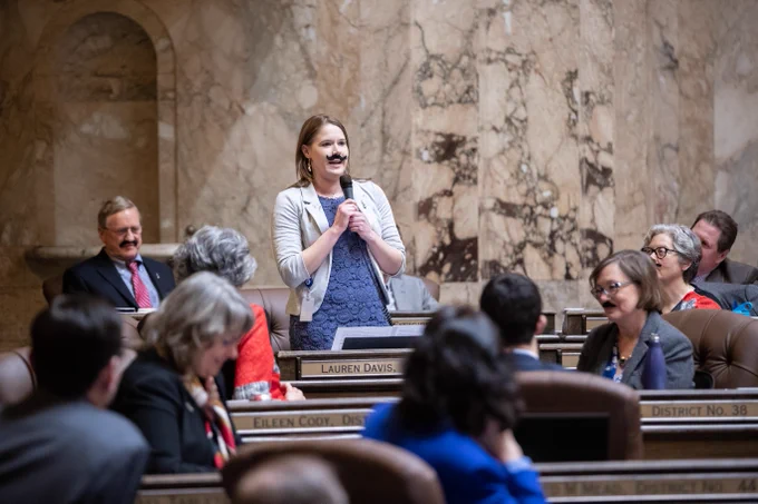 Rep. Lauren Davis reading a poem while rocking her "Frank Stache"
