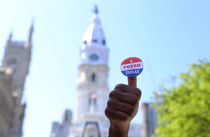 person giving a thumbs up with an "I voted" sticker on their thumb