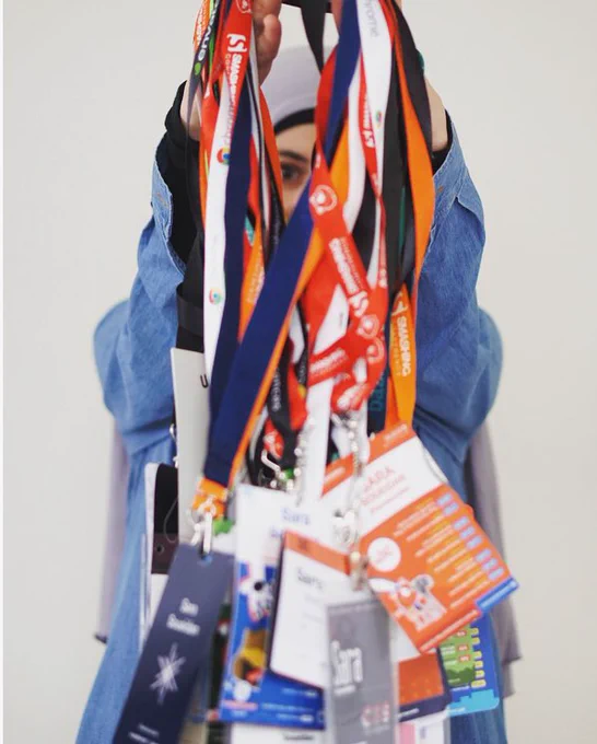 Me holding my conference badges; image focus on the lanyards