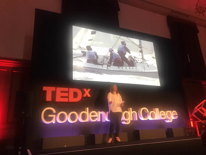 Hannah Stodel on the TedX stage with a picture of her sailing at the back