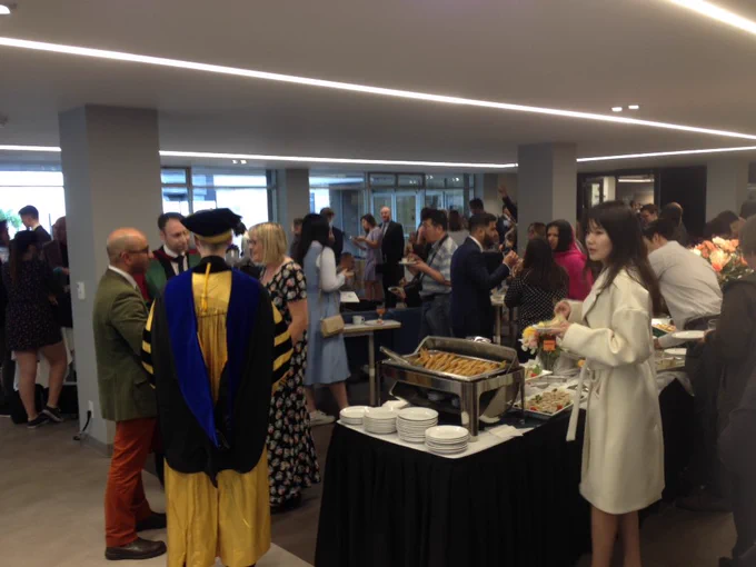 Academics and dignitaries chat by the buffet in the Coop.