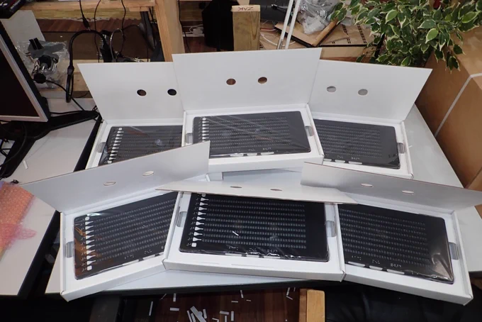 Six Canute 360 braille e-readers sitting in boxes on a table