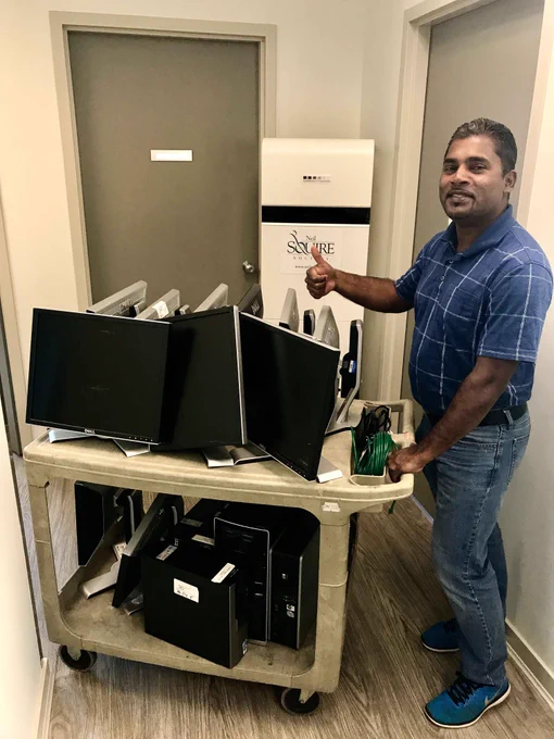 Munesh Raman, Computer Comfort co-ordinator, with a tray of desktop computers and monitors.