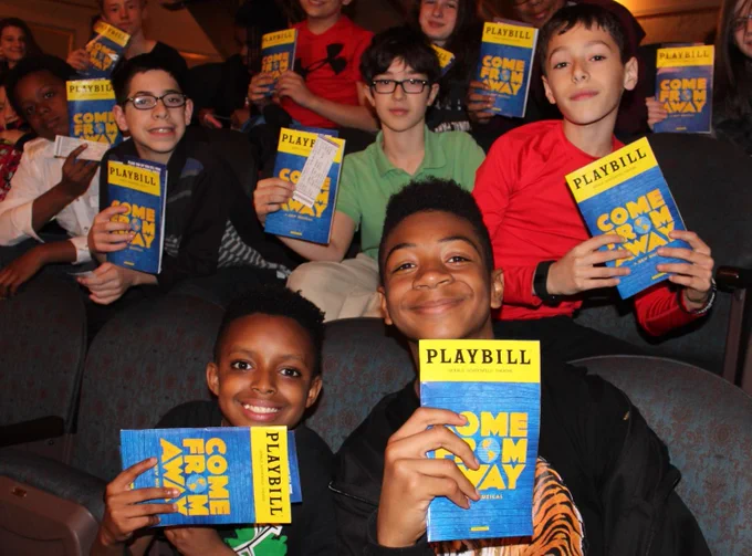 A group of middle school students at Come From Away - holding playbill