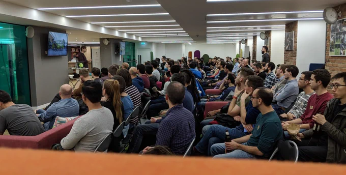room full of people listening to a person presenting