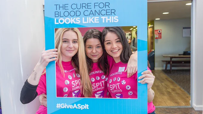 Three girls celebrate in a selfie frame at Loughborough University's #SpitHappens event, which registered students to the stem cell donor register in 2017