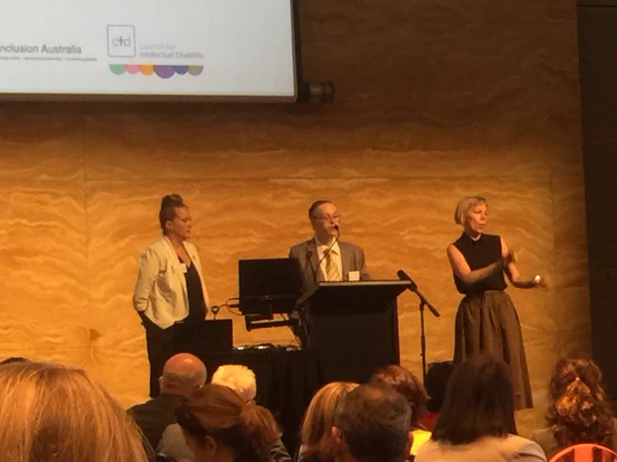 Image of Michael Sullivan from @nswcid speaking at podium with Auslan interpreter on the right.  #IDMHRT18