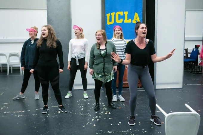 6 students singing in front of a banner with 'UCLA' on it during Legally Blonde rehearsals