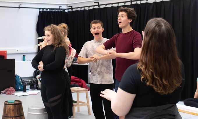 Students singing with their hands clasped in a rehearsal for Limbo: City of Dreams