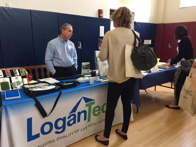 Conference attendee discussing assistive tech with LoganTech rep at exhibitor table