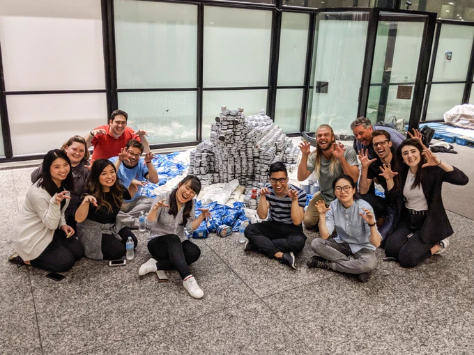 Twelve quadrangle staff sit around a polar bear structure made out of canned food