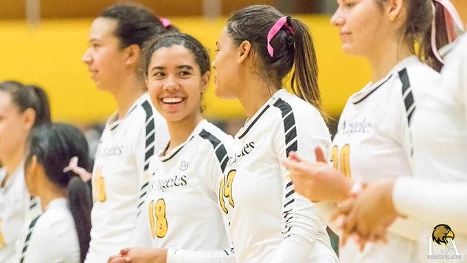 Volleyball players Bailey Anderson and Karla Santos smile at each other while talking.
