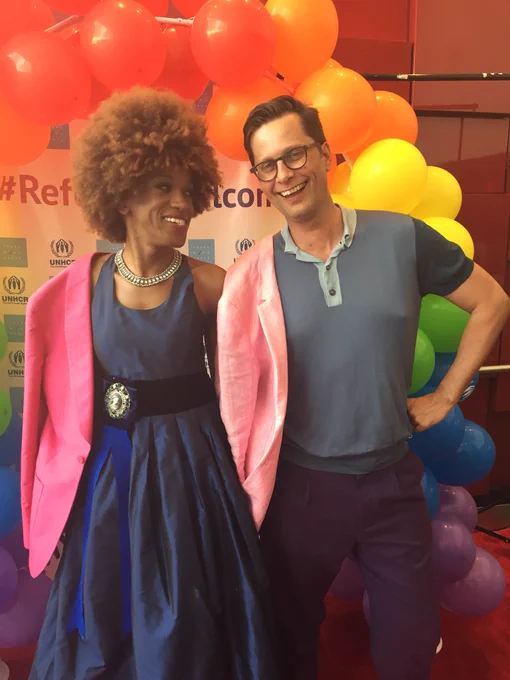 Trans Workforce founder Biko Beauttah and UNHCR Canada representative Jean-Nicolas Beuze pose in front of a rainbow arch at #RefugeesWelcome , a celebration of LGBTQ refugees