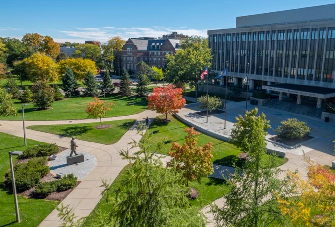 Overheard shot of campus near the Hannah Administration Building with a blue sky and colorful leaves hanging from trees
