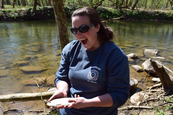 Woman with a big smile holding alewife by river