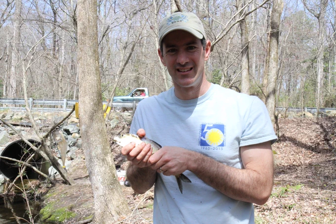 Man in baseball cap holding alewife