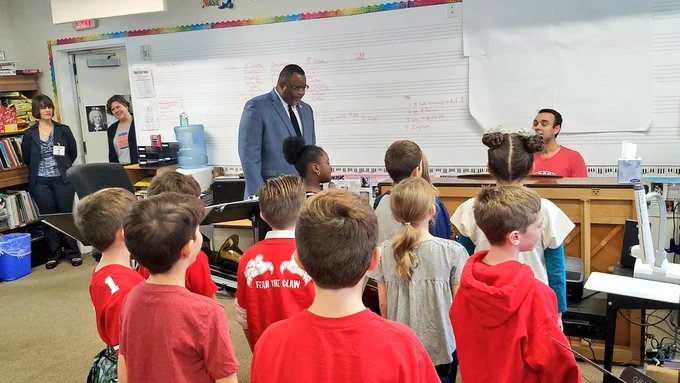 Dr. Repollet listening to students during music class