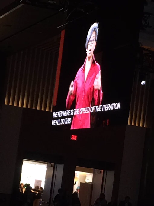 Ann Mei Chang speaking on a large screen. Caption: “The key here is the speed of the iteration”