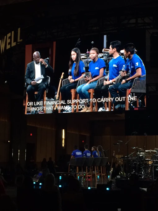 Four young people and a moderator sitting onstage. Caption: “or like financial support to carry out the things that I want to do”