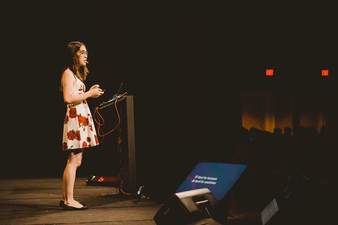 photo of me on conference stage wearing a white dress with roses pattern