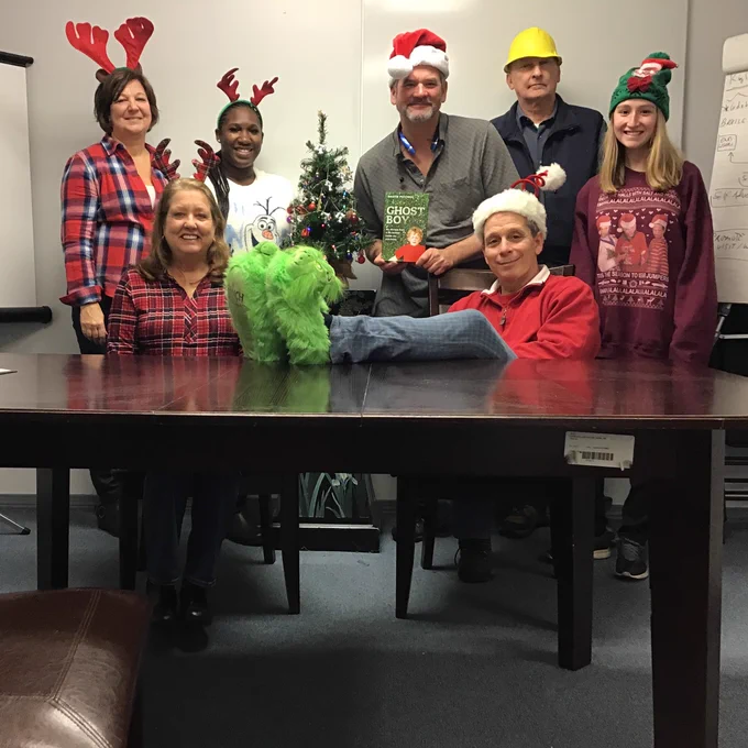 Picture: LoganTech staff in Christmas attire holding Ghost Boy book