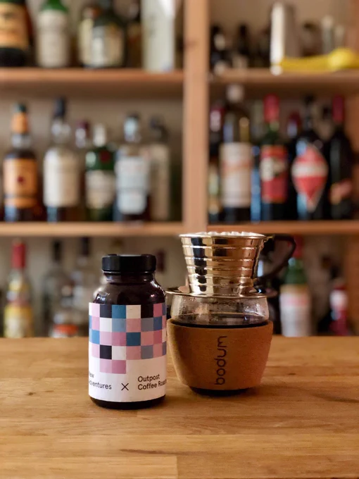 Photograph showing a small jar of coffee beans and a brewed cup of coffee.