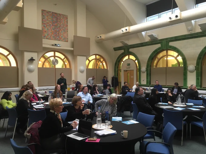 delegates at a conference, sitting at round tables.