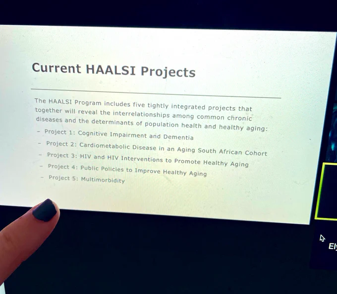 Finger pointing to a computer showing a presentation slide for a study about health in South Africa