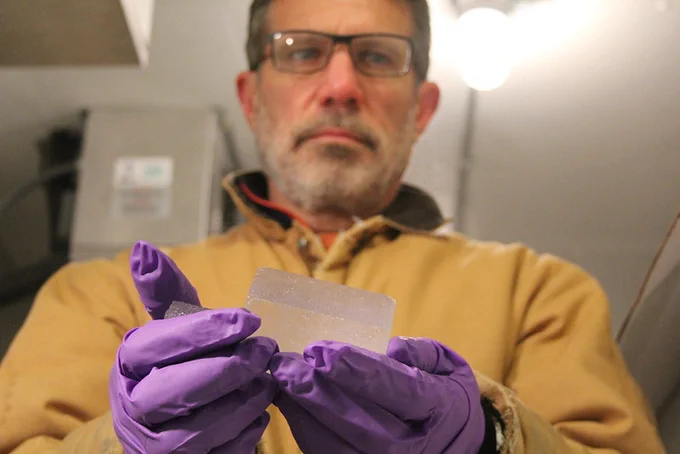 Oregon State Professor Ed Brook holds a piece of ancient ice in gloved hands. 
