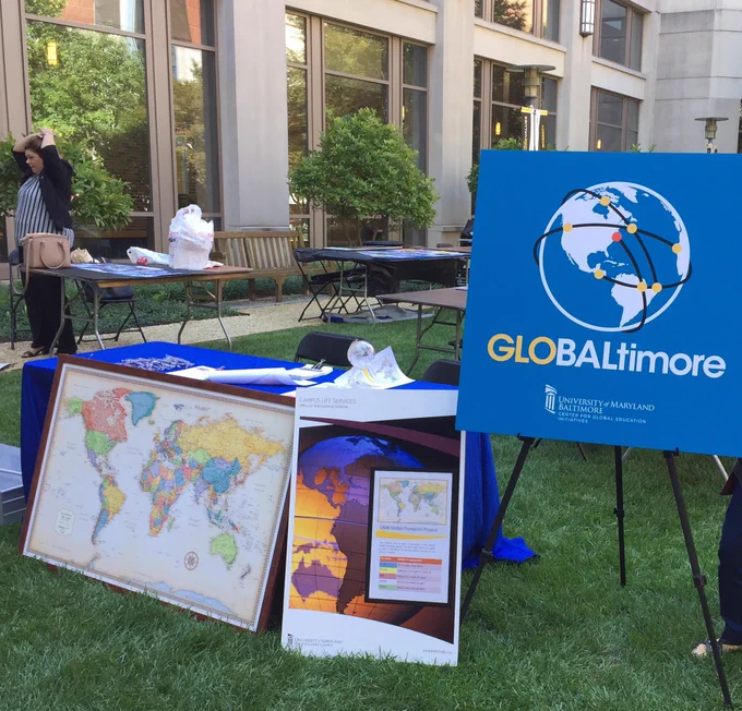 Table outside surrounded by posters with globes and maps. Other tables in the background.