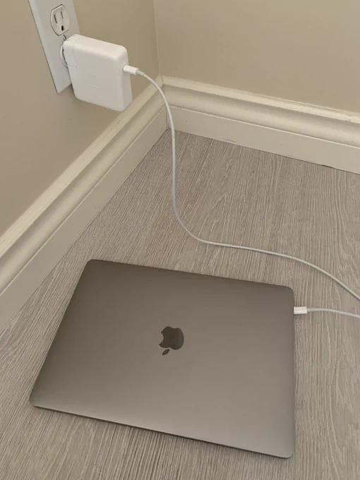 Charging my Macbook Pro on the floor of an empty room.