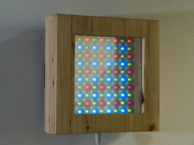 a wood box with a now-clear screen shows many individual red, green, and blue LED pixels
