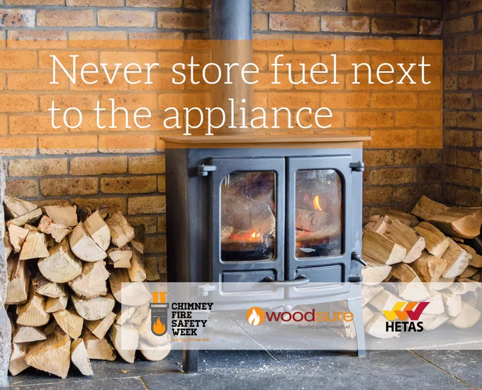 Never store fuel next to the appliance - an image of a wood burner in a brick recess with firewood stacked around it