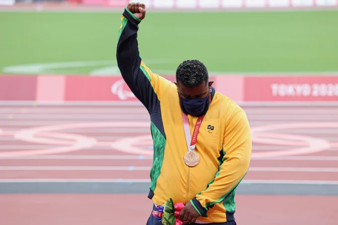 Thiago Paulino protesta de mão levantada com a medalha de bronze no pescoço