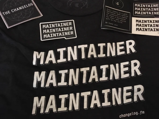 A black shirt that says "Maintainer" in white three times, and maintainer and Changelog stickers