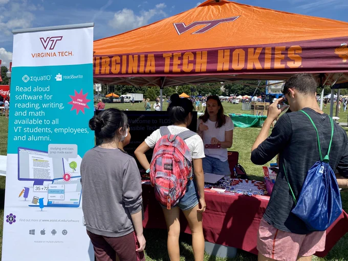Accessible technologies booth on the drillfield at VT with several students speaking with Megan Hagberg (graduate assistant) about Read&Write, EquatIO, Ally in Canvas, and the accessible technologies student club. 