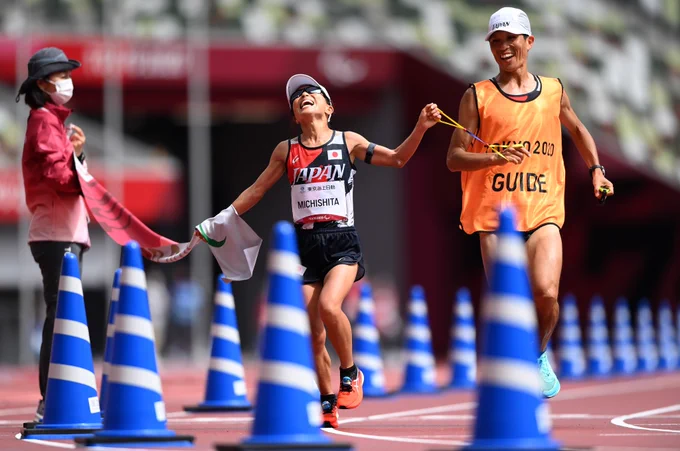 Misato Michishita of Team Japan reacts with her guide as she crosses the finish line to win the gold medal during the women's Marathon.