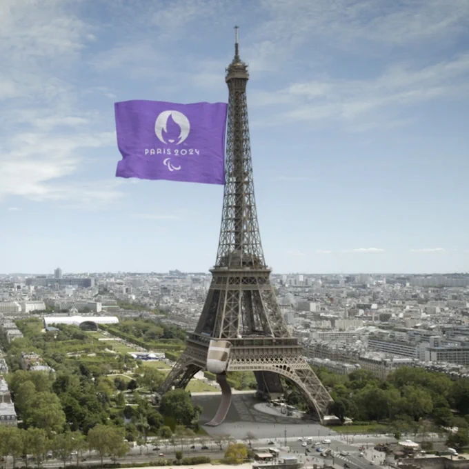 La Tour Eiffel est illustrée avec une prothèse remplaçant l'un de ses piliers. Un drapeau violet, en lien avec #WeThe15, est étendu sur la gauche de la tour. Il reprend le logo de Paris 2024 avec les agitos, symboles du mouvement paralympique.