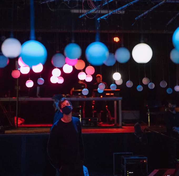 Person standing under some glowing orbs looking up at them